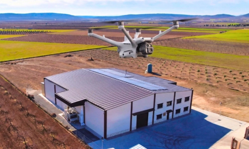 Dron multirrotor industrial en vuelo técnico sobre la cubierta con paneles solares y fachada de una fábrica en producción en Toledo para el curso de inspección de infraestructuras de Toledrón.