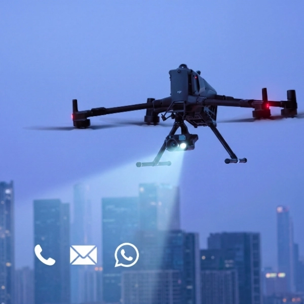 Dron industrial DJI Matrice en vuelo nocturno proyectando un haz de luz sobre iconos de contacto de teléfono, email y WhatsApp para la página de contacto de Toledrón.