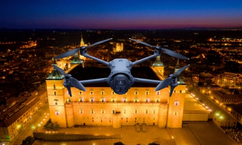 Dron profesional con cámara cinematográfica en vuelo frontal nocturno frente al Alcázar de Toledo iluminado para el curso de filmación aérea y fotografía para cine y televisión de Toledrón.