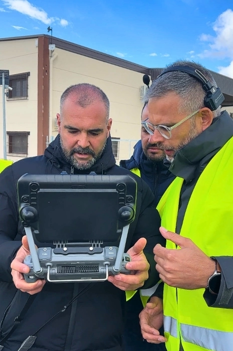 Instructor de Toledrón con cascos de radiocomunicación explicando parámetros de telemetría en la pantalla de una emisora inteligente industrial a dos alumnos en las prácticas de inspección con drones.